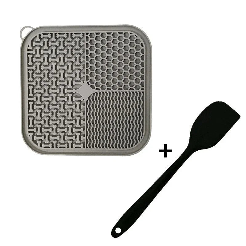 Square silicone dog lick mat with textured surface and black spatula on white background