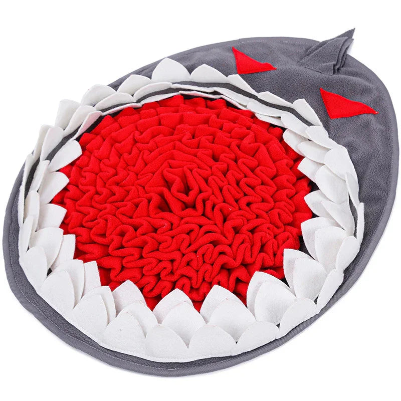 Shark-shaped pet snuffle mat with red center and white teeth for interactive feeding.