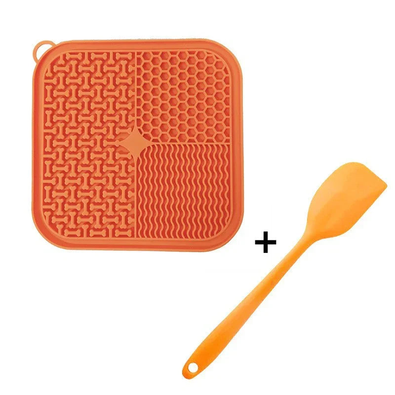 Orange silicone pet licking mat with textured patterns and matching spatula